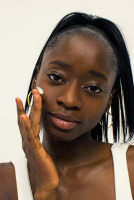 beautiful black woman puts sunscreen on her face