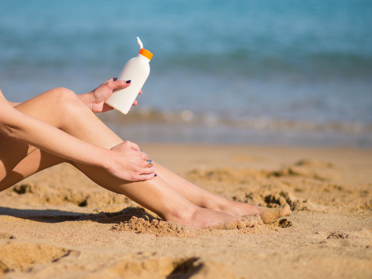 woman on the beach putting on sunscreen
